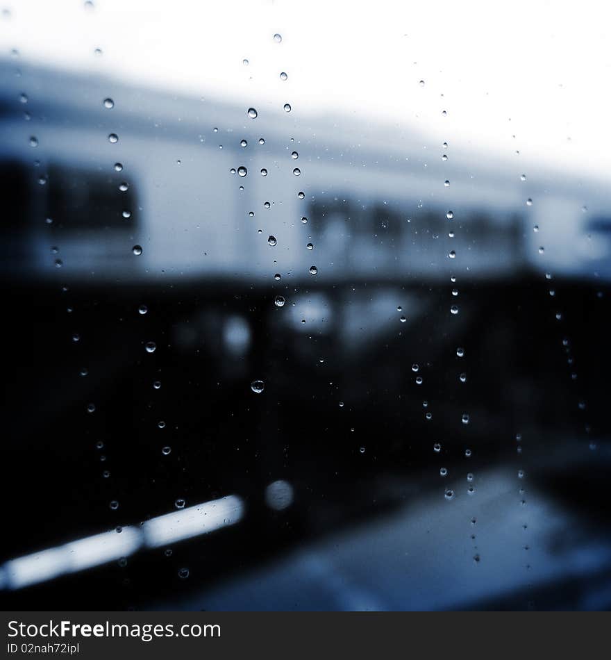 Rain drops on the window on a rainy day. The Building in the backdrop is a local railway station in Tokyo. Rain drops on the window on a rainy day. The Building in the backdrop is a local railway station in Tokyo.