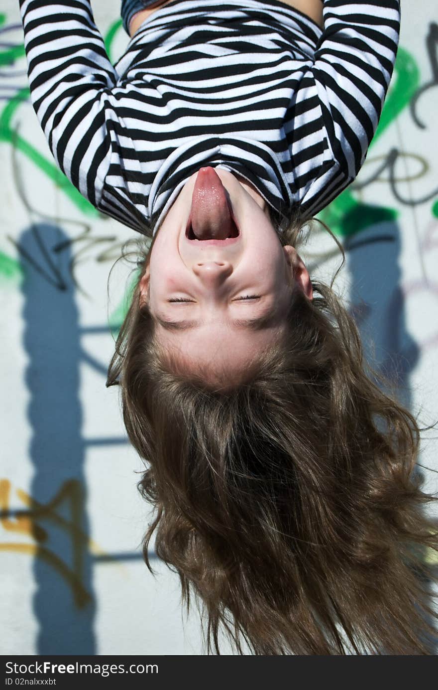 A cute little girl in a sailor's striped vest doing exercises and putting tongue out. A cute little girl in a sailor's striped vest doing exercises and putting tongue out