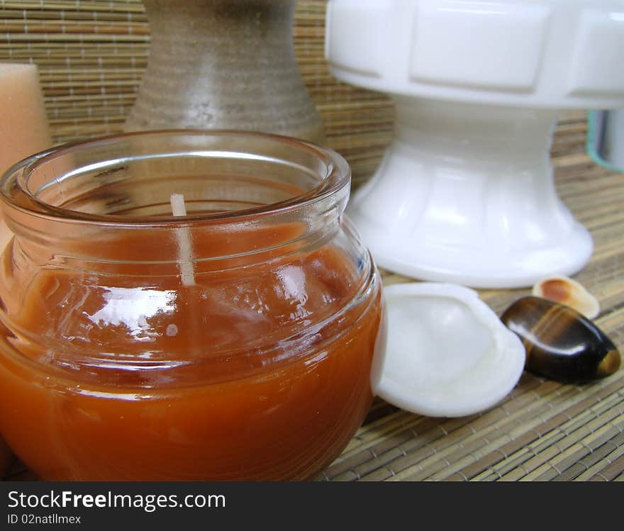 Red-brown votive candle with shells, vase and jar