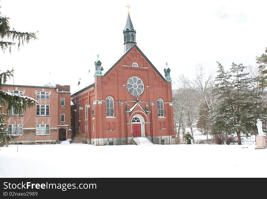 An old red church sitting in the snow.