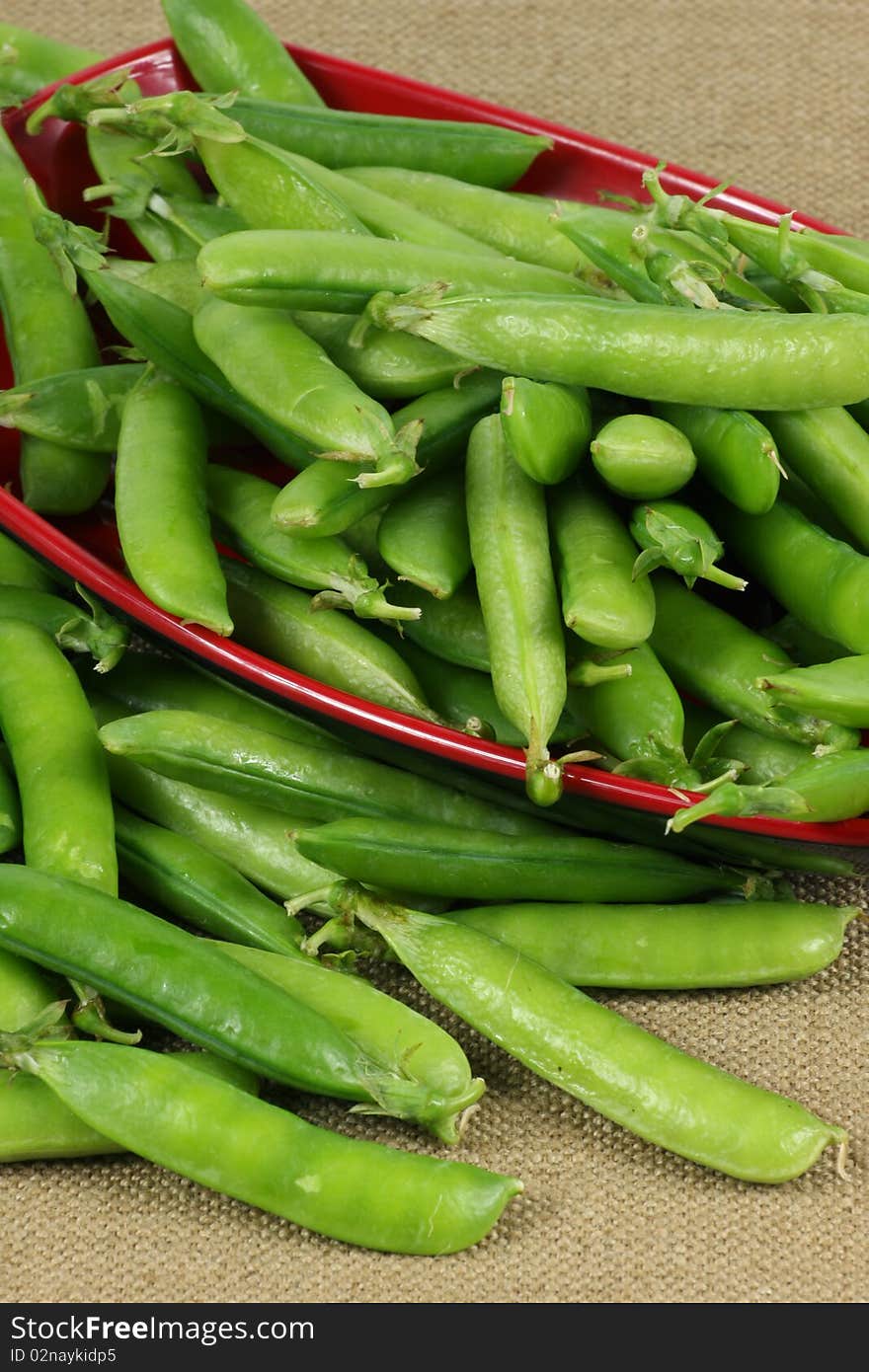 Delicious fresh green peas on red plate. Delicious fresh green peas on red plate