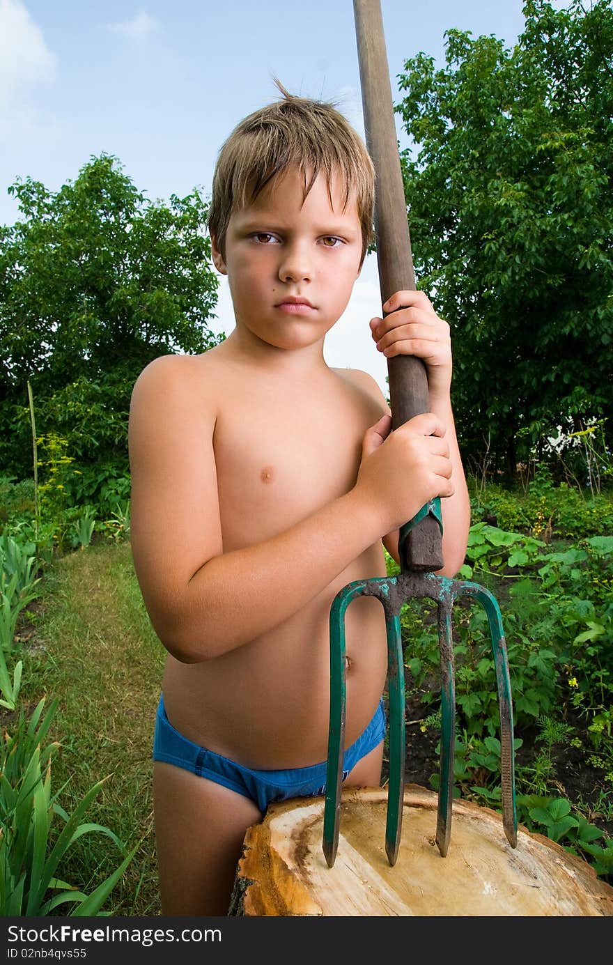 White serious boy with a pitchfork on the nature