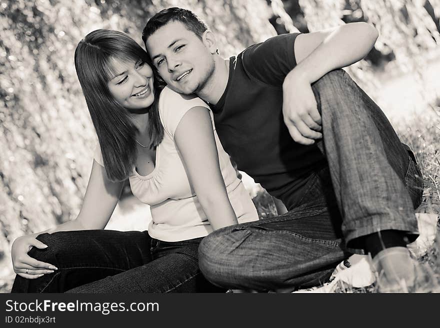 Portrait of cheerful couple sitting under the tree