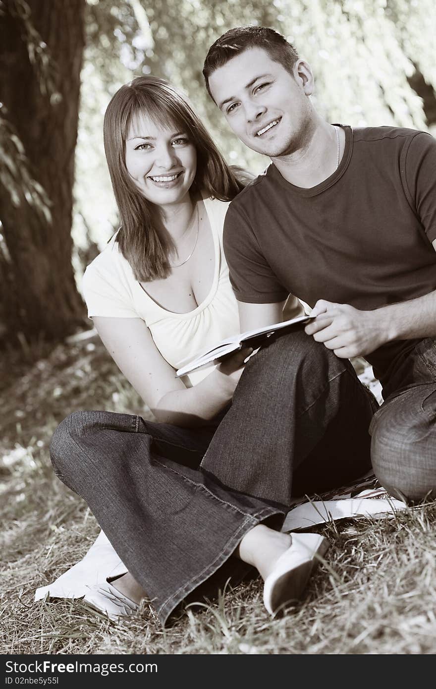 Young happy couple reading a book outdoors