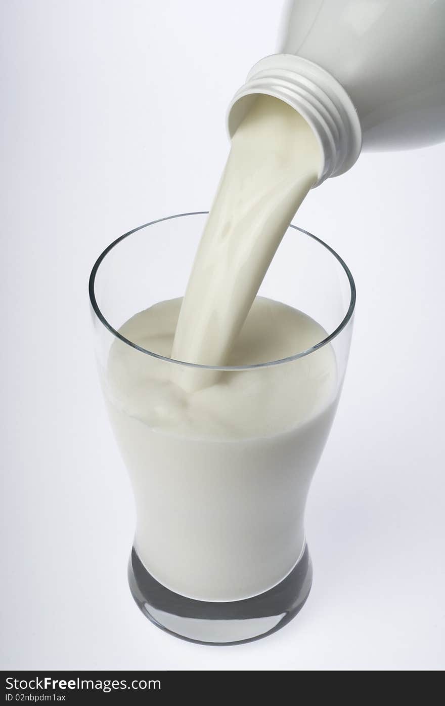 Close up of milk being poured into a glass on white background