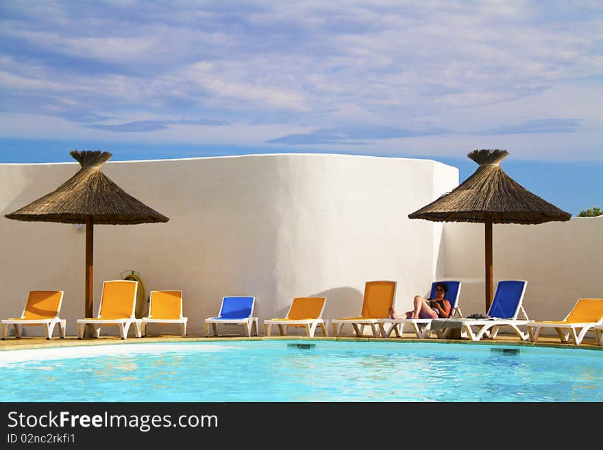 Swimming pool with lounge chairs and thatched umbrellas. Swimming pool with lounge chairs and thatched umbrellas