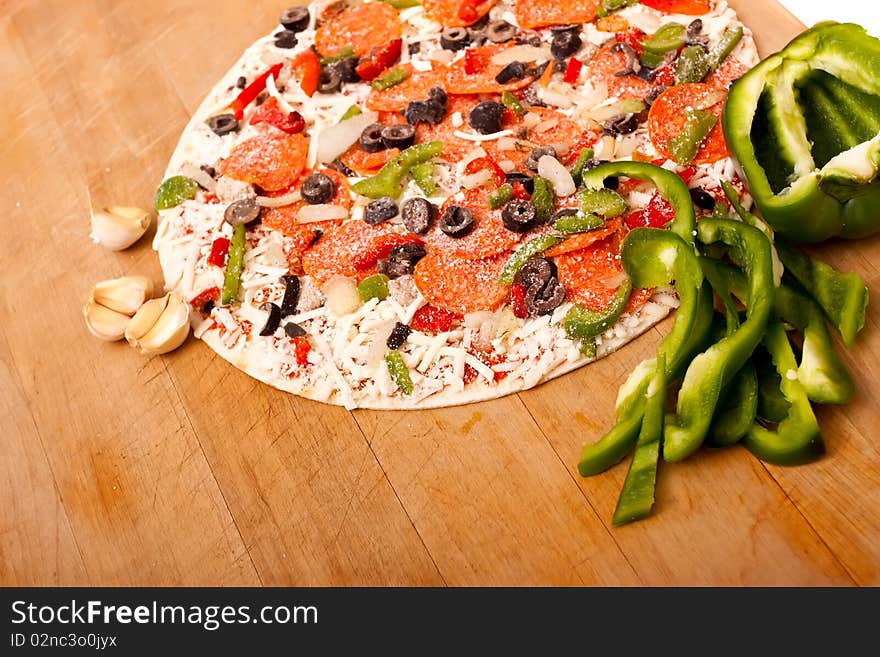 Raw pizza with vegetables and pepperoni