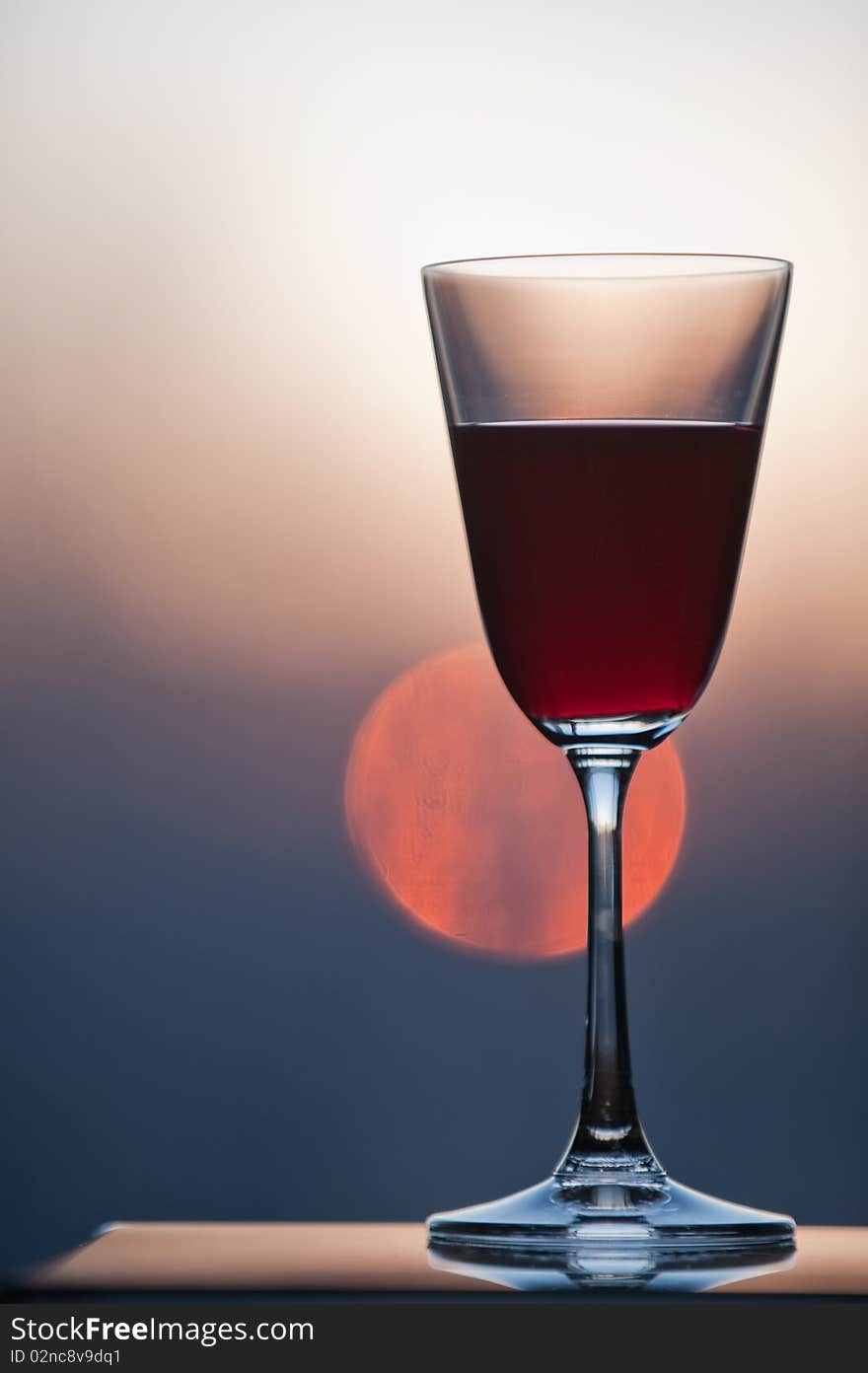 Closeup of a glass of wine with setting sun in background. Closeup of a glass of wine with setting sun in background