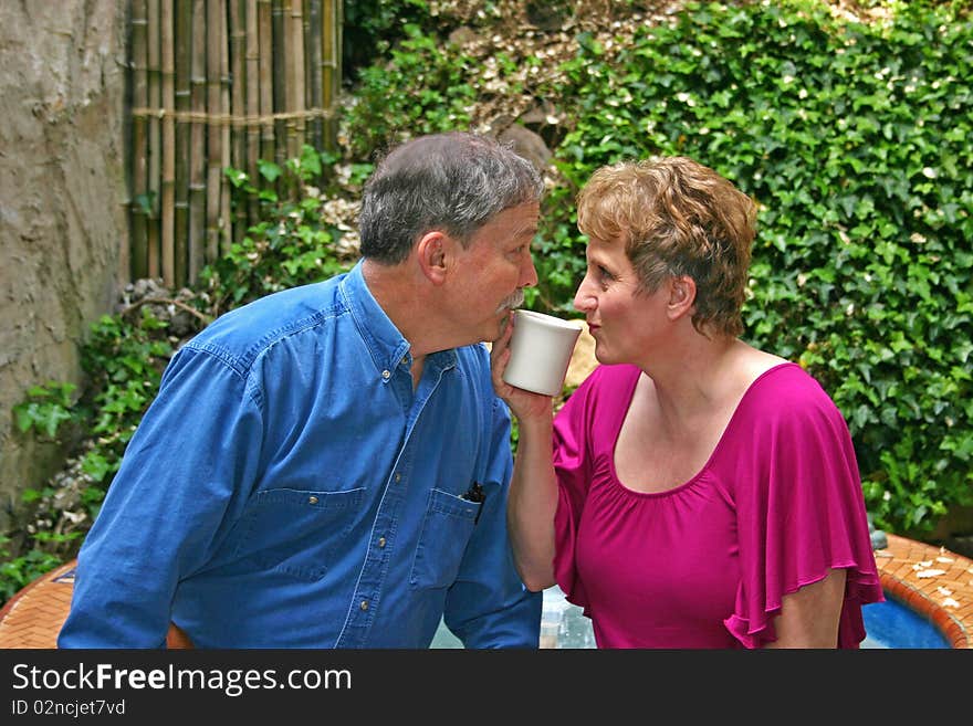 A middle-aged couple flirting over a cup of coffee. A middle-aged couple flirting over a cup of coffee