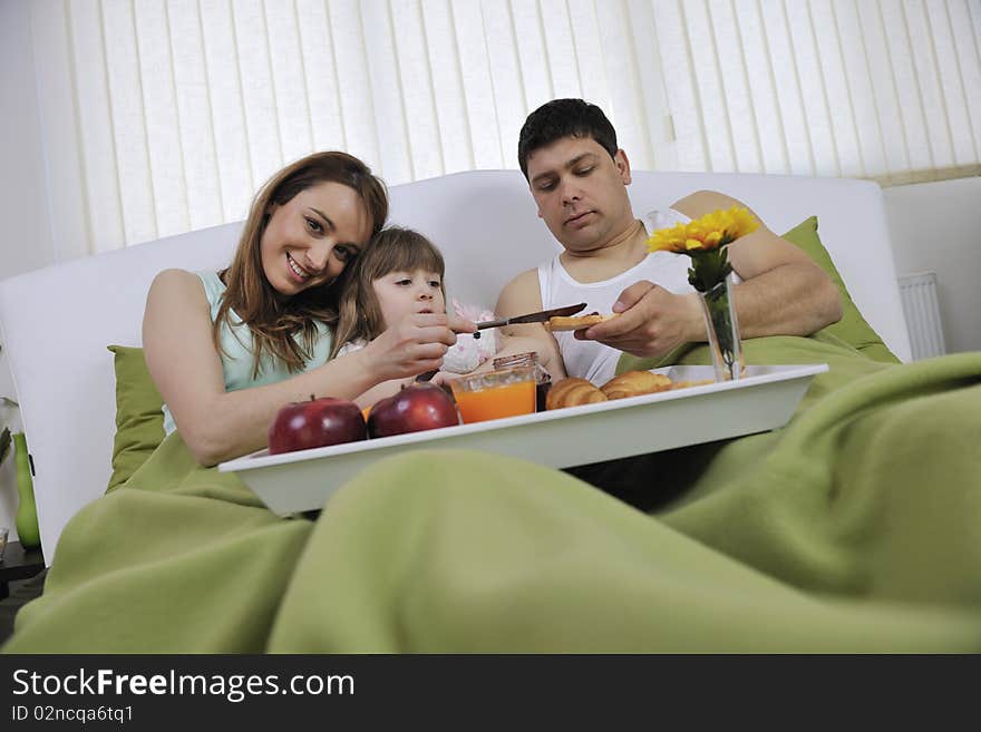 Happy young family eat breakfast in bed