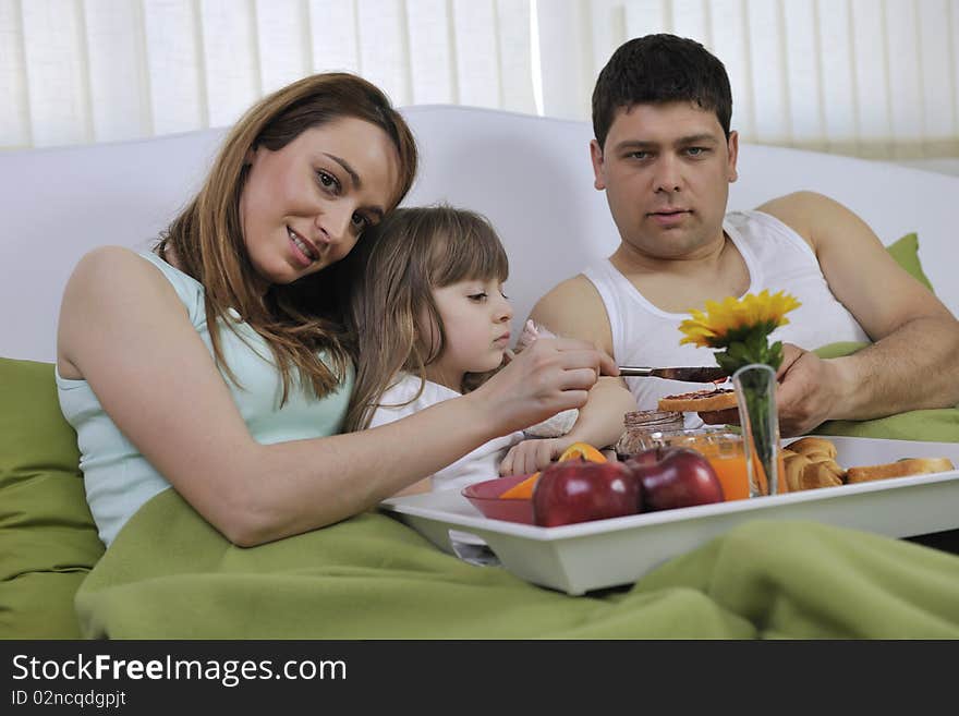 Happy young family eat breakfast in bed