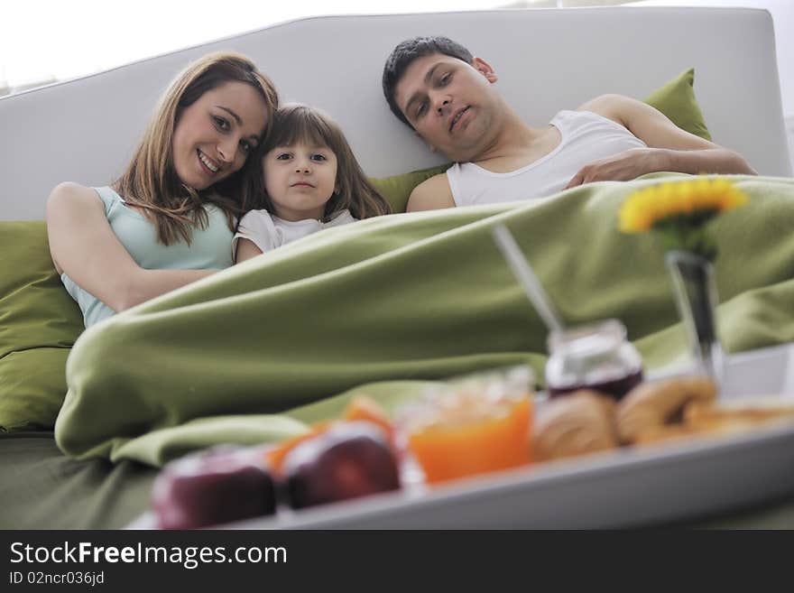 Happy young family eat breakfast in bed at morning