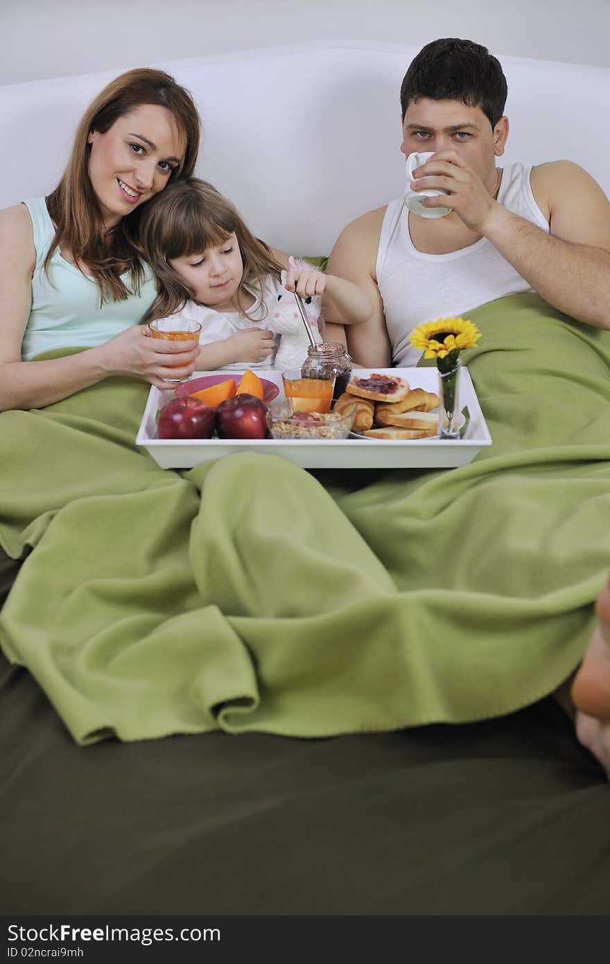 Happy Young Family Eat Breakfast In Bed