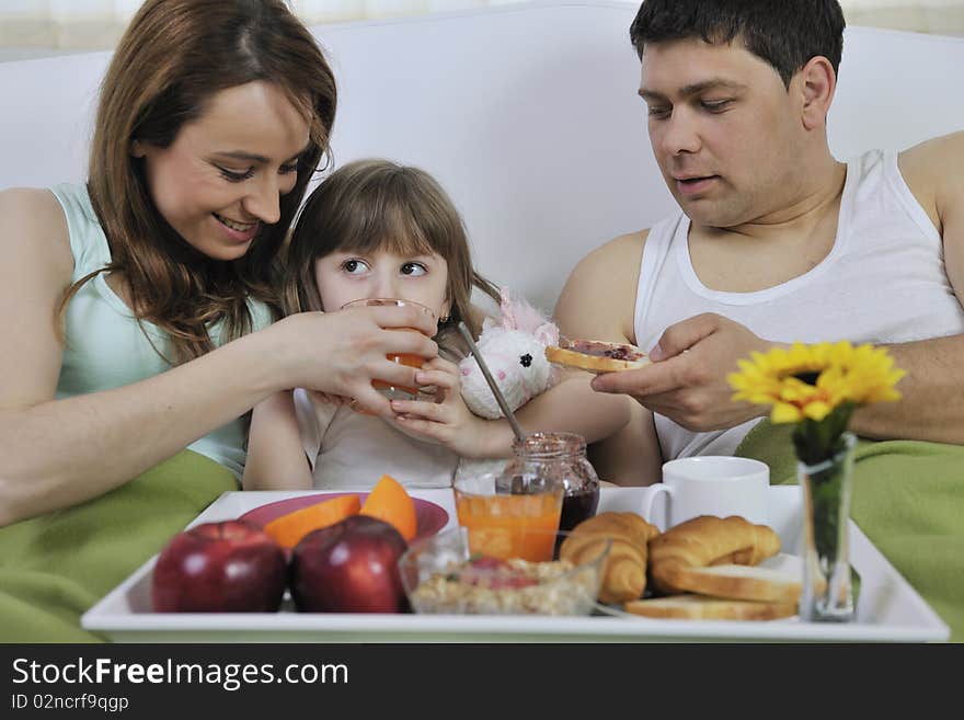 Happy young family eat breakfast in bed at morning