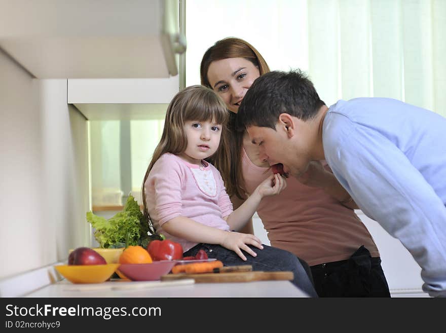 Happy young family have lunch time with fresh fruits and vegetable food in bright kitchen. Happy young family have lunch time with fresh fruits and vegetable food in bright kitchen