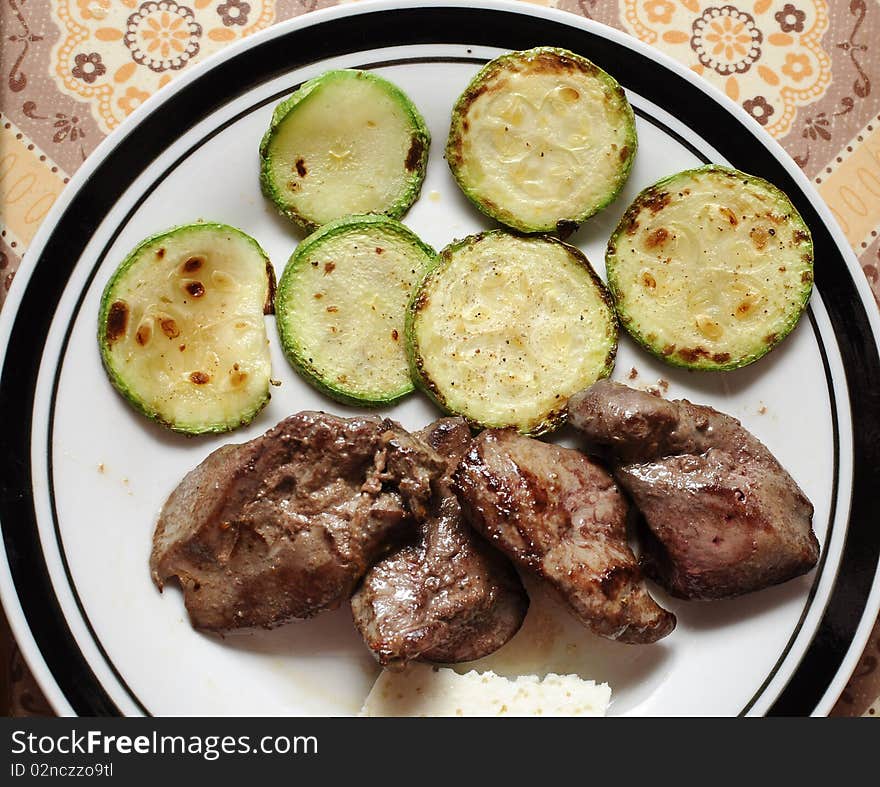 Slices of green and yellow Italian zucchini, pan fried and sprinkled with herbs. Served on white plate with black lining. Slices of green and yellow Italian zucchini, pan fried and sprinkled with herbs. Served on white plate with black lining.