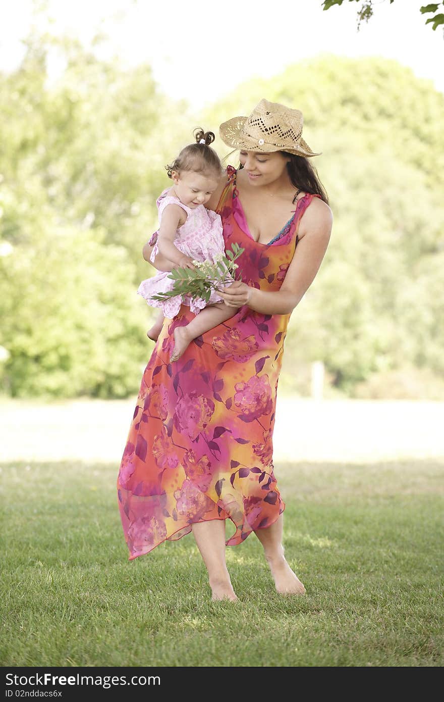 Mother holding her daughter while out for a walk in the park. Mother holding her daughter while out for a walk in the park