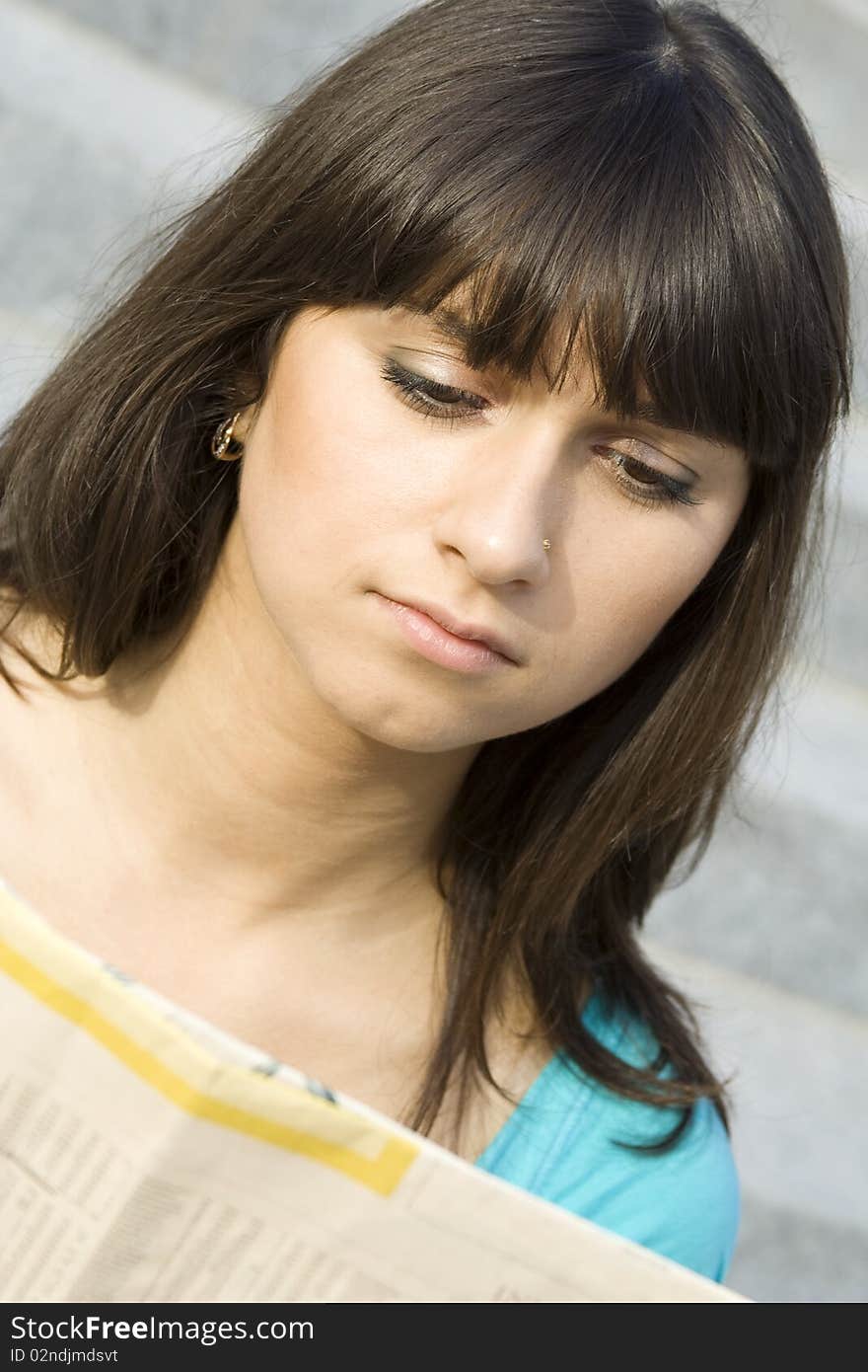 Young woman reading a newspaper outdoors