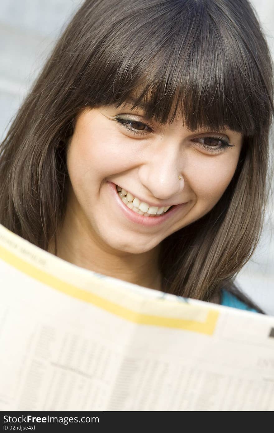 Young woman reading a newspaper outdoors