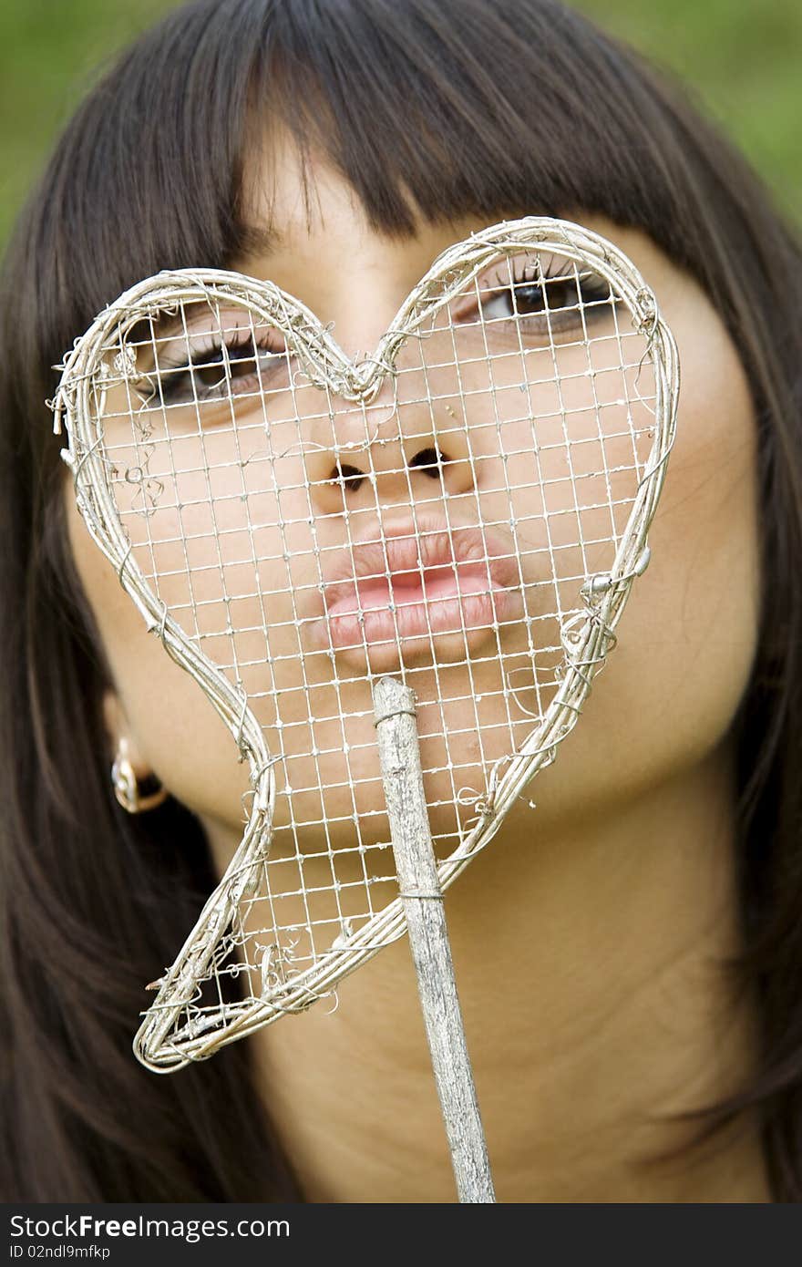 Female kissing her lips together in the face of the decoration in the form of heart. Female kissing her lips together in the face of the decoration in the form of heart