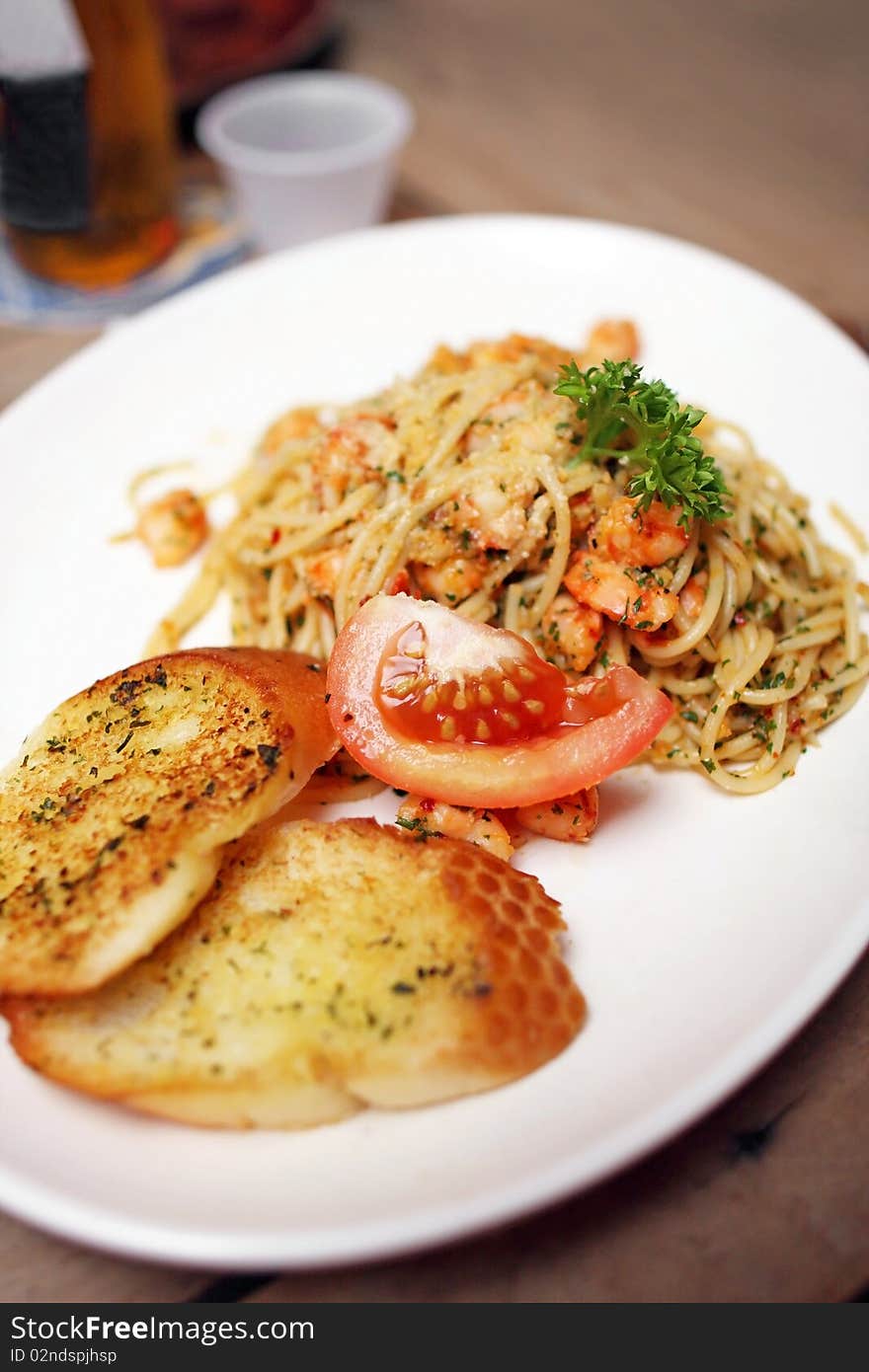 Close up of seafood spaghetti with tomato and garlic bread.