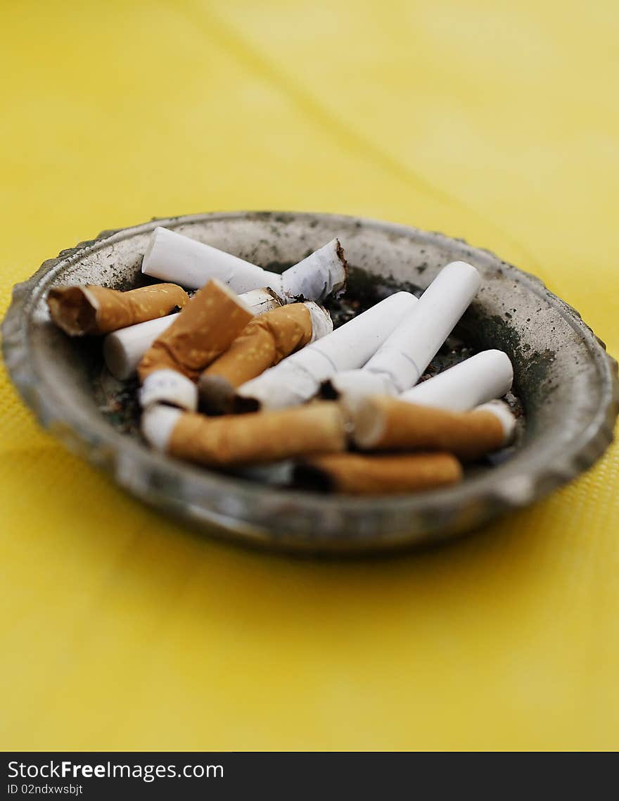 Cigarettes in ashtray on yellow background