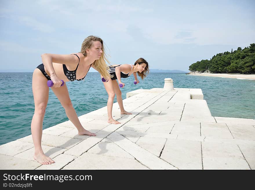 Young students lifting weights on the beach