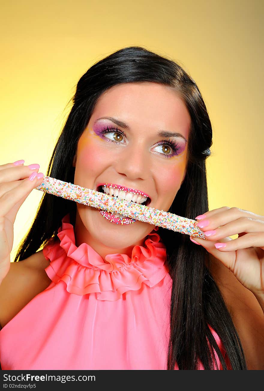 Beautiful happy girl with a sweet lollipop and creative makeup . yellow background