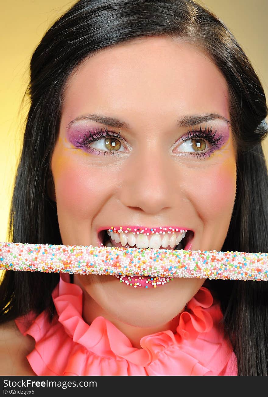 Beautiful happy girl with a sweet lollipop and creative makeup . yellow background