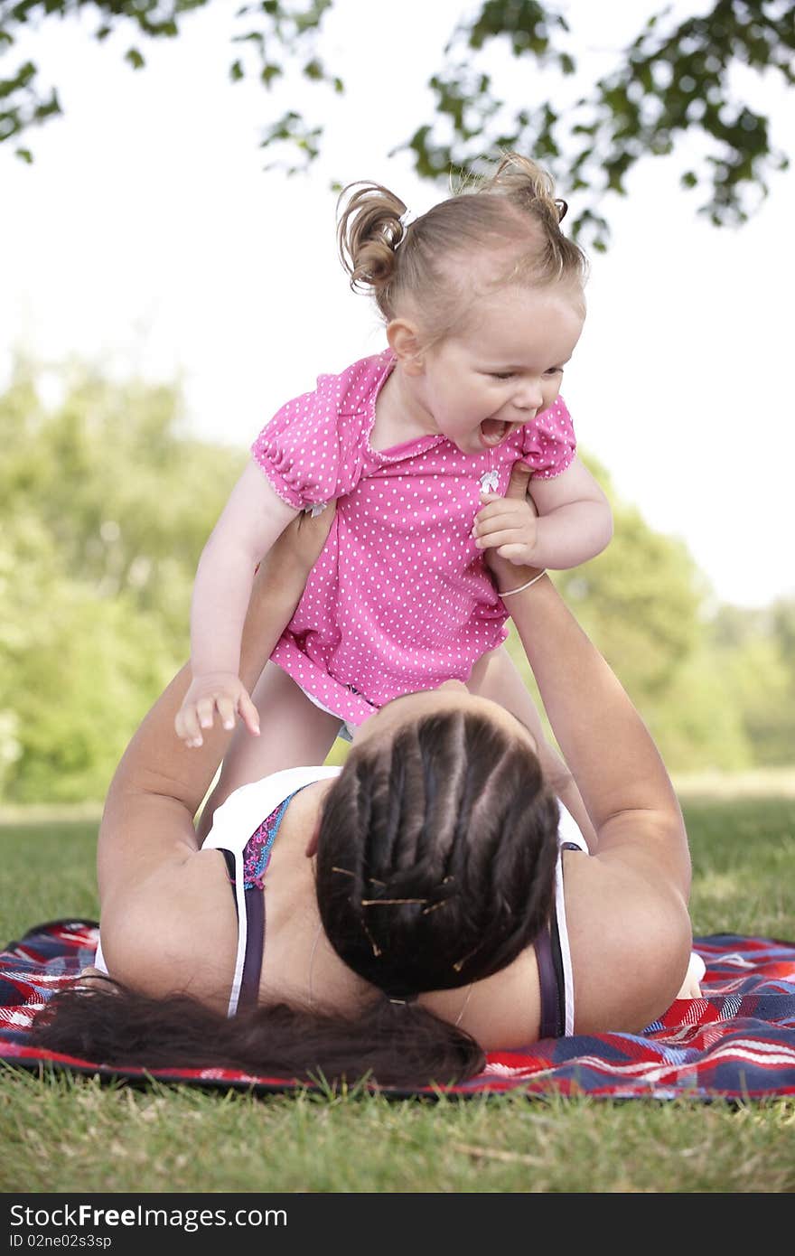 Mother playing with daughter in the park in summer