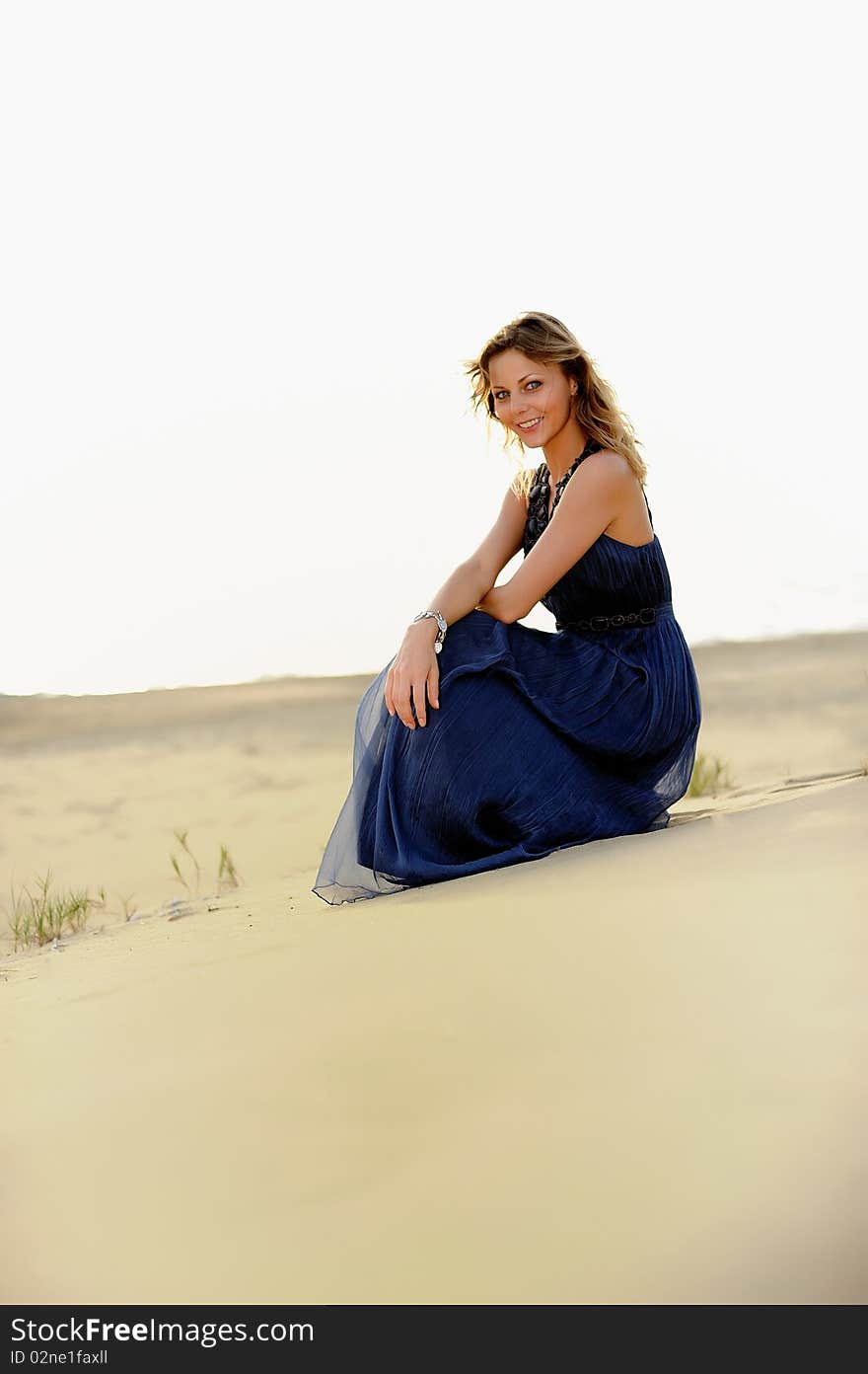 Beautiful woman sitting on the beach in a sand