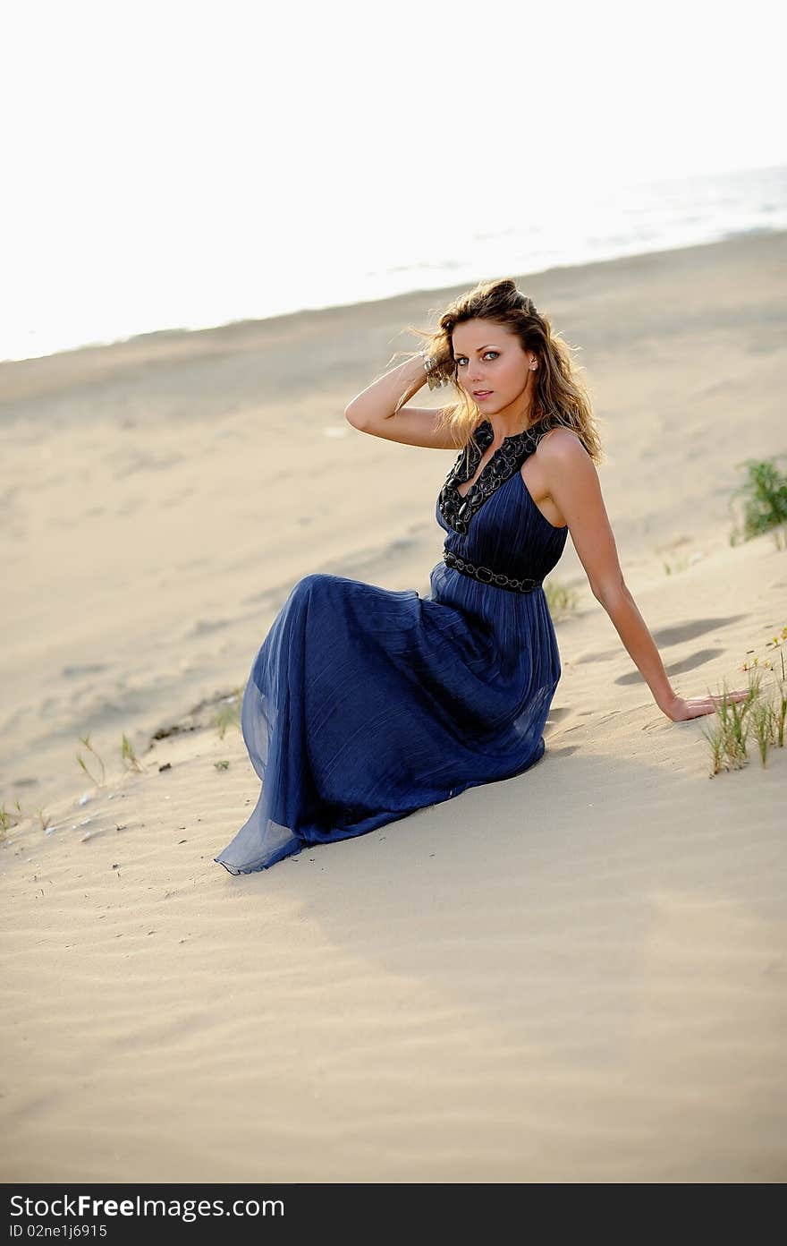 Beautiful Woman Sitting On The Beach In A Sand