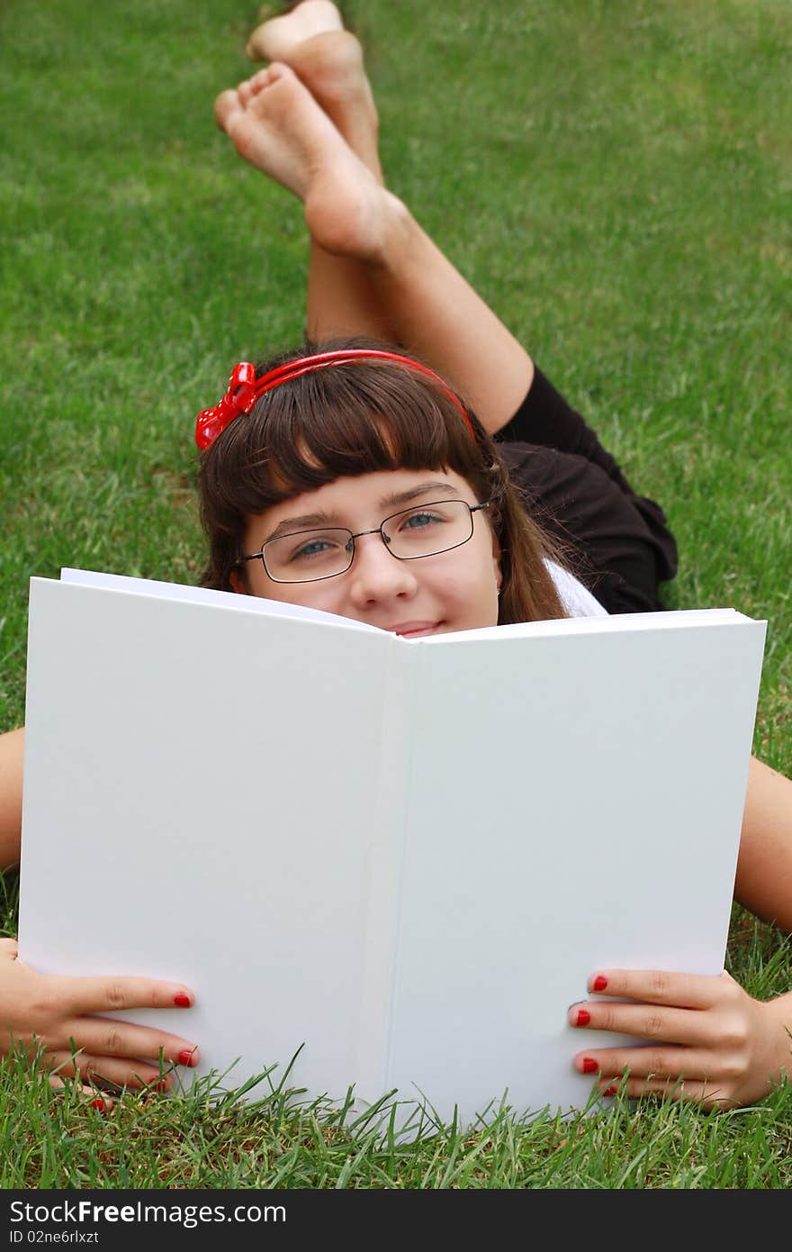 Pretty girl on a grass looking over the book. Pretty girl on a grass looking over the book