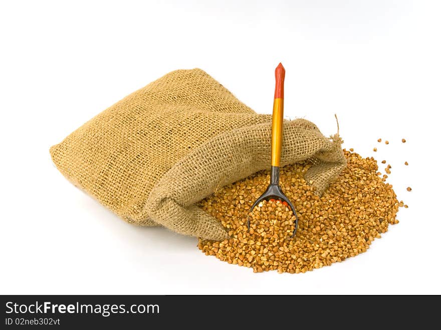 Bag with scattered buckwheat and wooden spoon