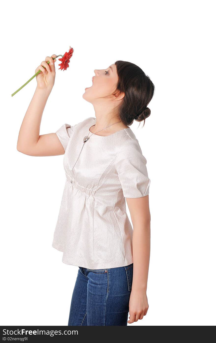 Charming young girl in blue jeans and a white blouse with a red flower in the hands