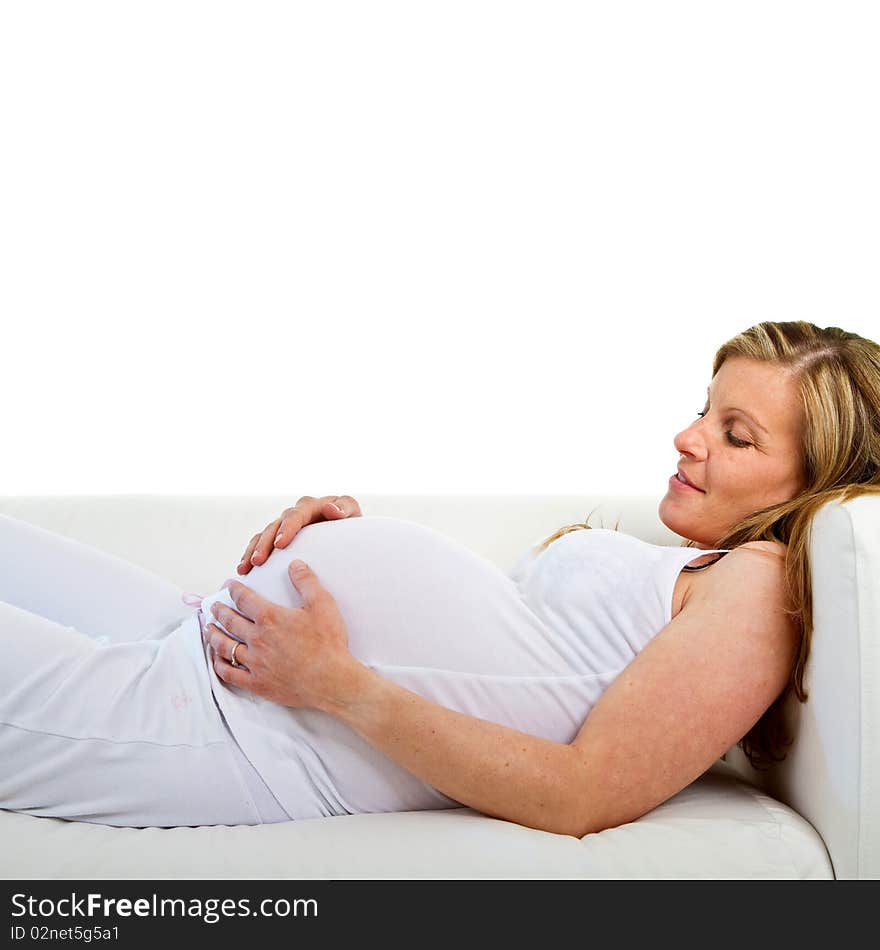 Young fresh pregnant woman lying on a stylish white couch over white background. Young fresh pregnant woman lying on a stylish white couch over white background.