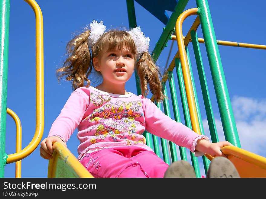 In the summer on a children's playground the child sits on a hill. In the summer on a children's playground the child sits on a hill