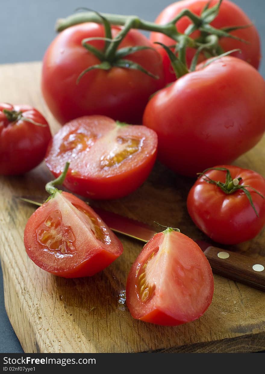 Whole and half fresh tomatoes on a board