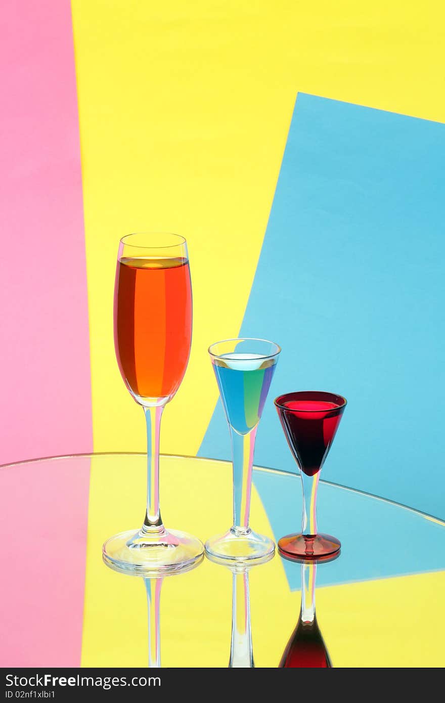 Three wine-glasses on multi-coloured background