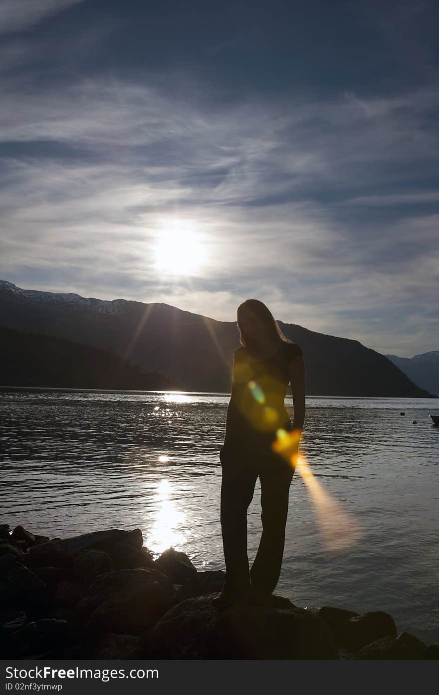 Shot of a woman posing in front of sunset on a fjord