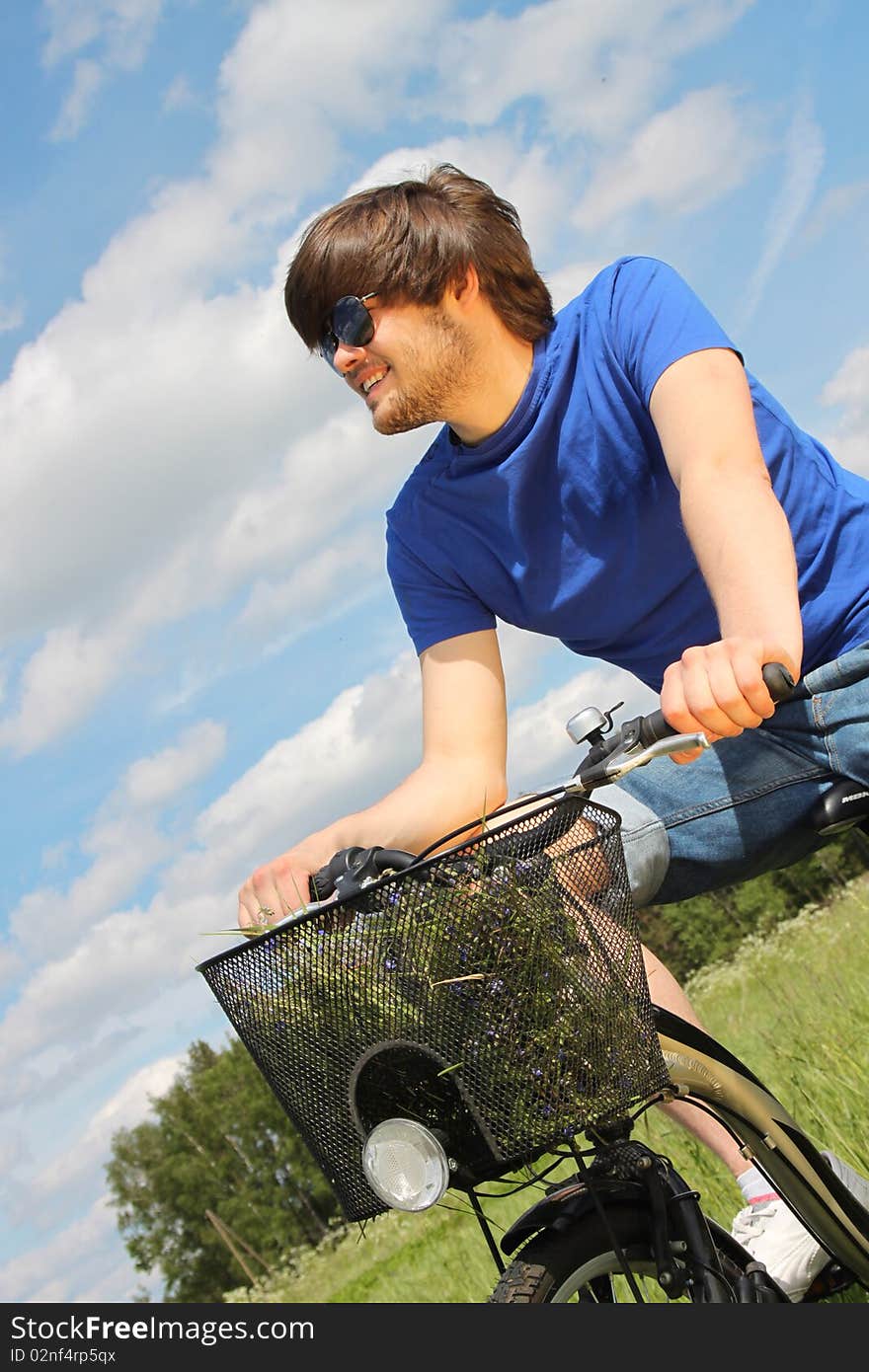 Young handsome man riding a bike in the middle of meadow