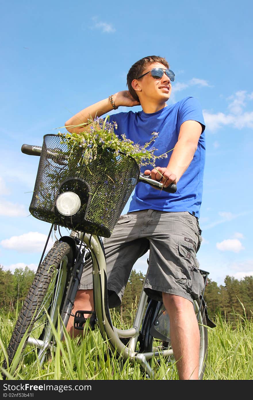 Young handsome man riding a bike in the middle of meadow