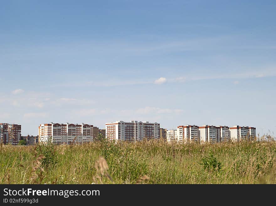 Appartment buildings against the blue sky and green field