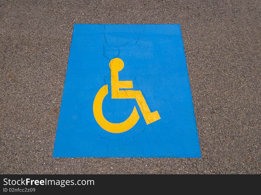 Handicap symbol painted on black asphalt parking lot