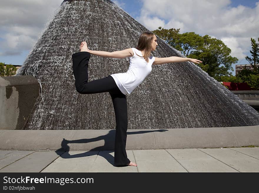 A woman doing a yoga pose in a park in front of a waterfall. A woman doing a yoga pose in a park in front of a waterfall.