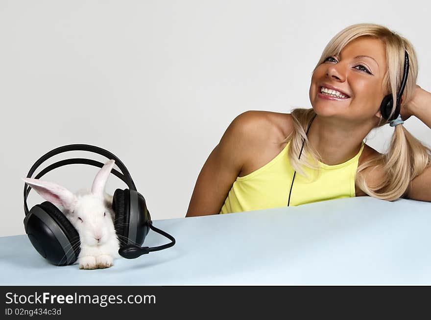 Smiling blond and white rabbit listening to music with headphones