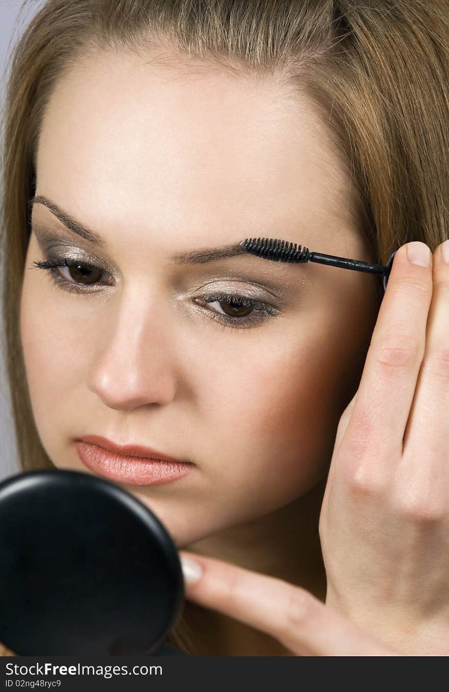 Pretty young woman applying make up.