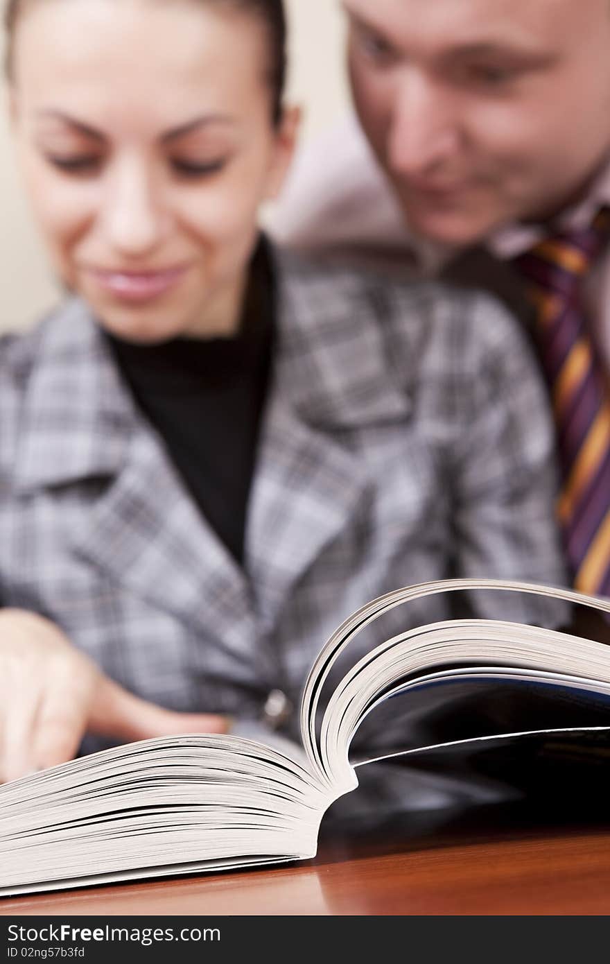 Young man and woman reading large textbook. Young man and woman reading large textbook