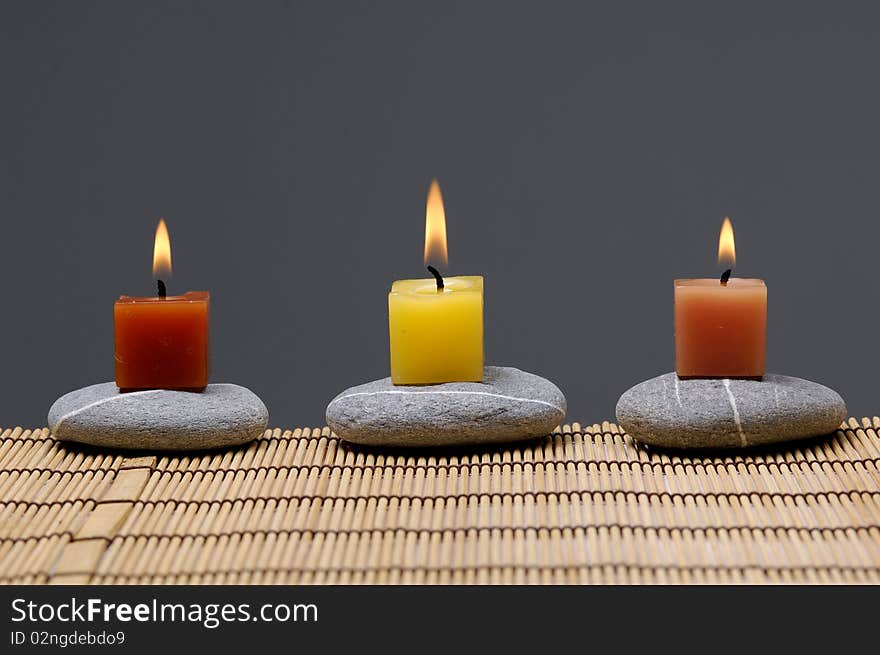 Colorful alight candle on row of stones. Colorful alight candle on row of stones