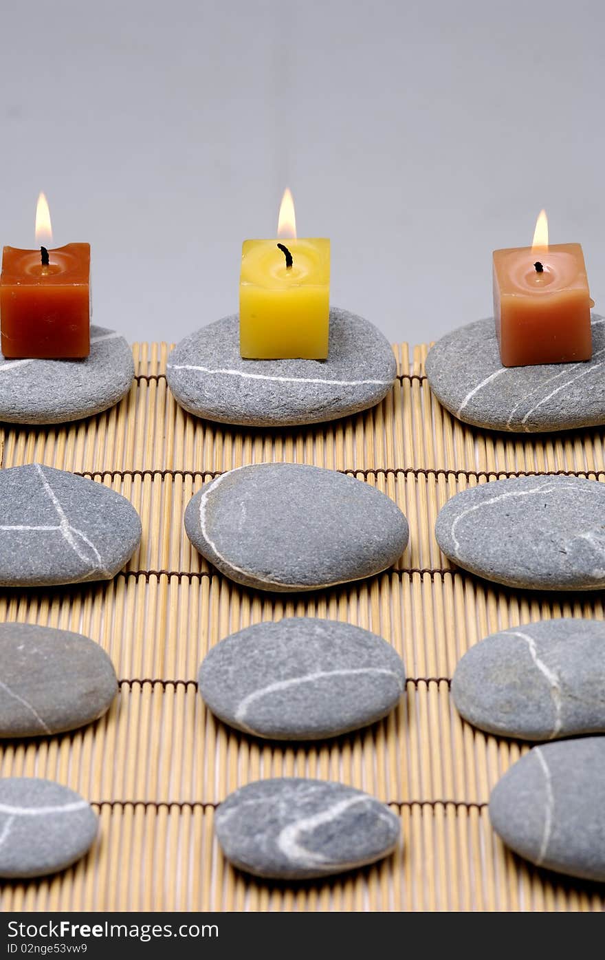 Colorful alight candle on row of stones